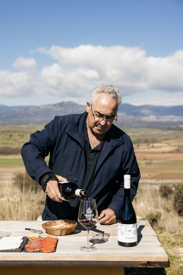 Winemaker pouring red wine above Viña Bardela vineyards