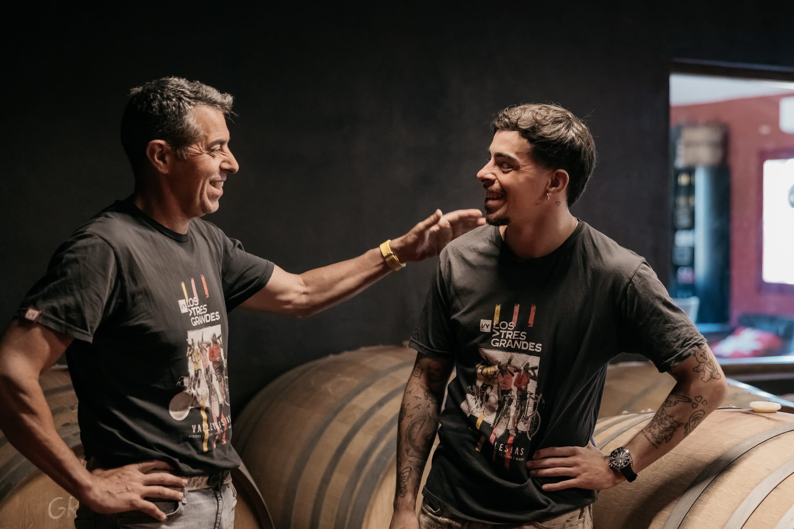 ValleYglesias team laughing beside wine barrels